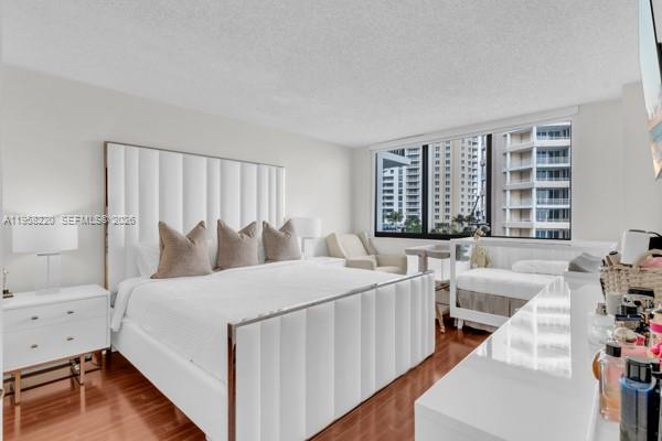 A bedroom with a white upholstered bed, a crib, and a large window overlooking buildings — 540 Brickell Key Dr # 832, Miami FL 33131, MIAMI, FL