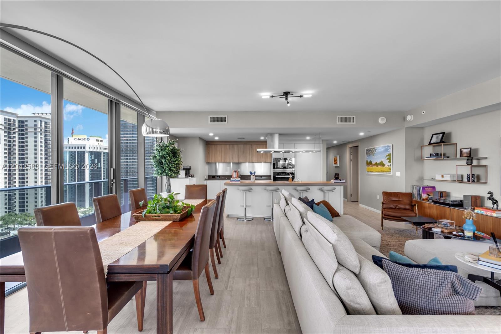 An open-concept living and dining area features a modern kitchen, floor-to-ceiling windows, and city views — 1000 Brickell Plz # 2402, Miami FL 33131, MIAMI, FL