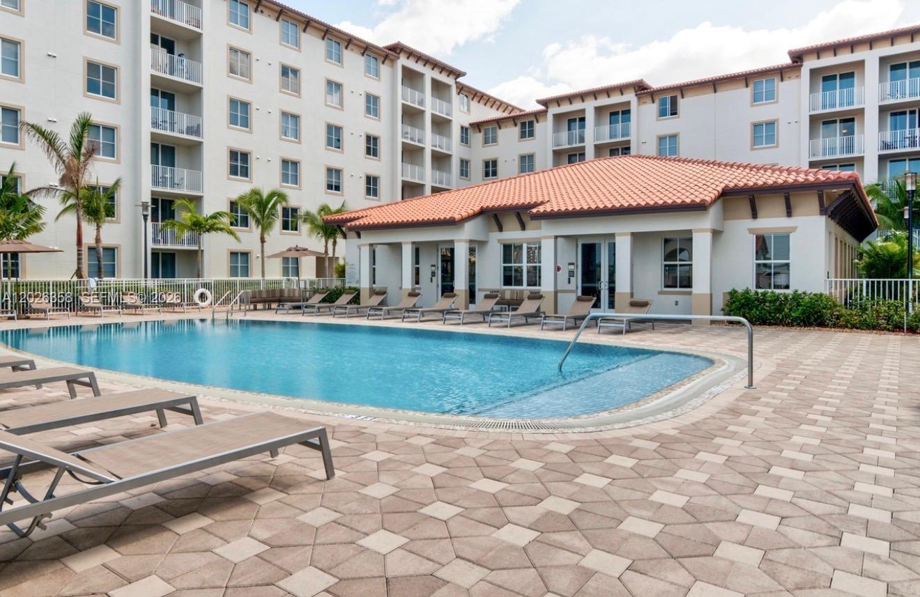 A swimming pool sits in front of a multi-story apartment building with a clubhouse — 8290 Lake Dr # 143, Doral FL 33166, DORAL, FL