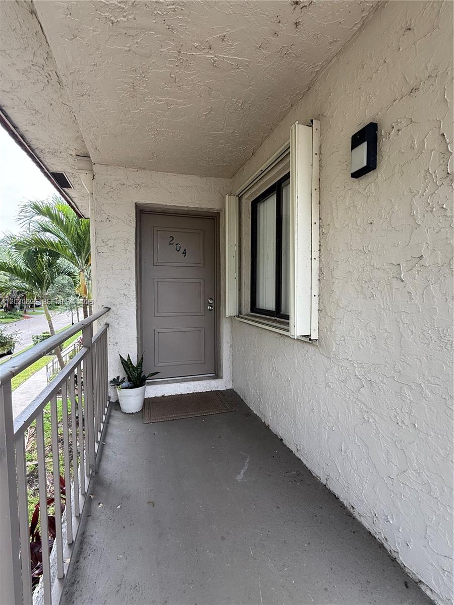 An exterior balcony features a gray door numbered 204, a window, and a metal railing — 16184 Laurel Dr # 204, Weston FL 33326, WESTON, FL
