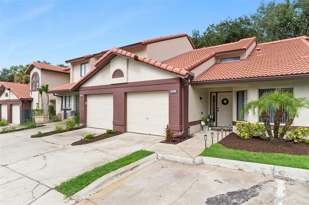 A two-story townhouse with a two-car garage, stucco exterior, and a red tile roof — 3344 GRAY FOX COVE UNIT 4, APOPKA, FL