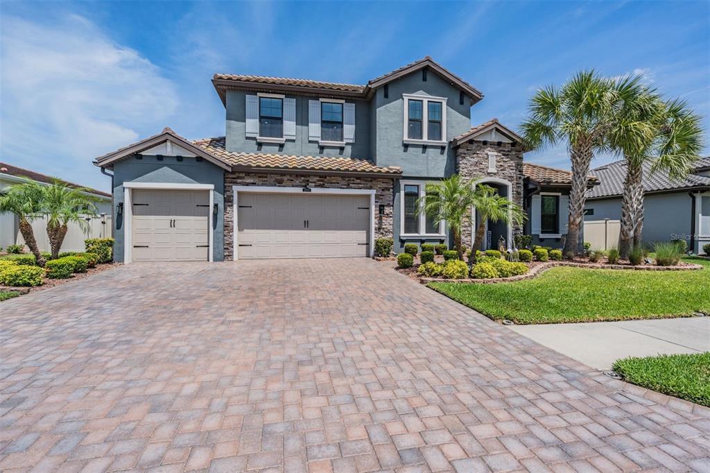 A two-story house with a stone facade, a three-car garage, and a paved driveway — 29043 PICANA LANE, WESLEY CHAPEL, FL