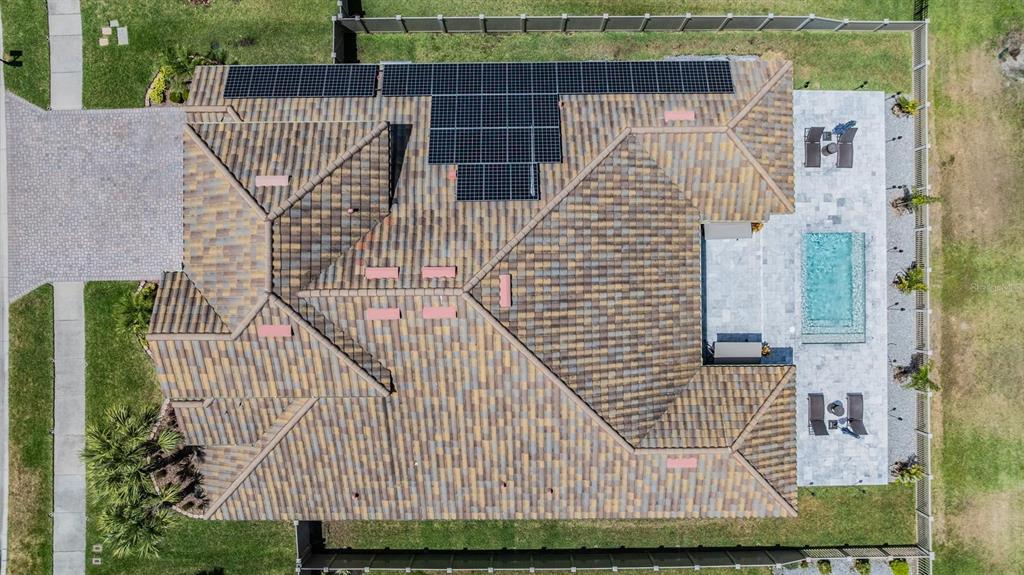 An aerial view shows a house with a tiled roof, solar panels, and a backyard pool — 29043 PICANA LANE, WESLEY CHAPEL, FL