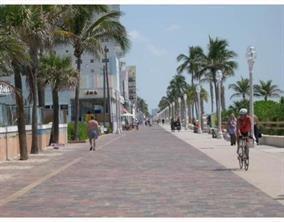 A paved boardwalk lined with palm trees and streetlights runs alongside buildings and a beach — 301 Van Buren Street # 101d, Hollywood FL 33019, HOLLYWOOD, FL