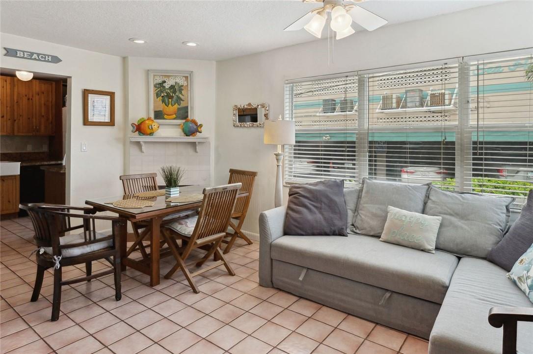 A living and dining area features tile flooring, a grey sofa, and a wooden table — 301 Van Buren Street # 101d, Hollywood FL 33019, HOLLYWOOD, FL