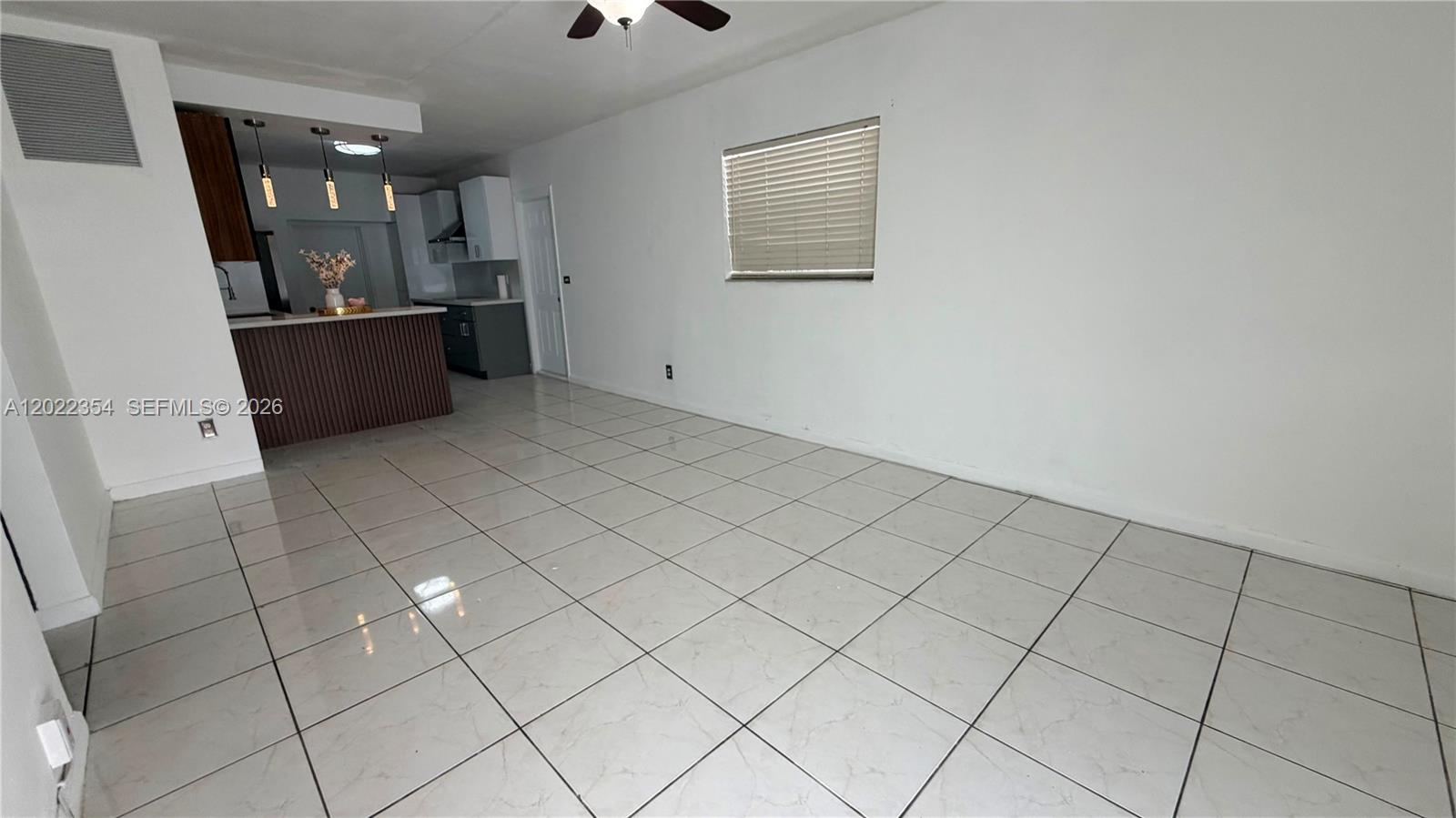 An open-concept living area features white tile flooring, a ceiling fan, and a kitchen island — 3610 SW 39th Ave, West Park FL 33023, WEST PARK, FL