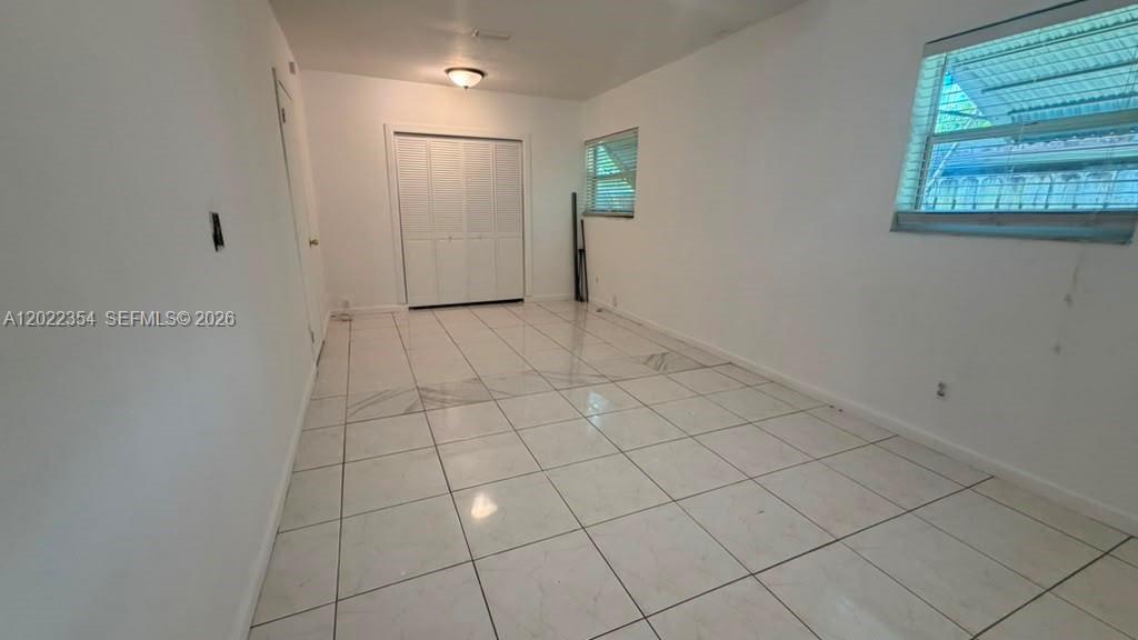 An empty room features white tiled floors, white walls, and a white louvered closet door — 3610 SW 39th Ave, West Park FL 33023, WEST PARK, FL