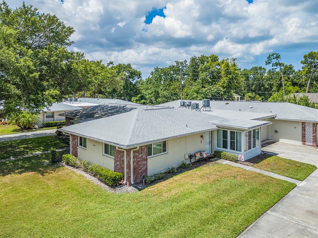 An exterior view of a single-story house with a gray roof and brick accents — 1009 QUEEN ANNE DRIVE UNIT B, PALM HARBOR, FL