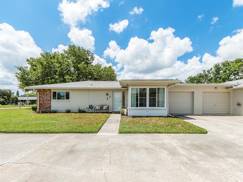 A single-story house with a white exterior, two garage doors, and a front lawn — 1009 QUEEN ANNE DRIVE UNIT B, PALM HARBOR, FL