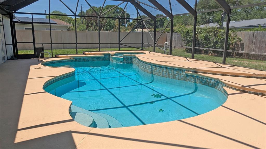A screened-in backyard swimming pool with a built-in spa and light-colored concrete decking — 1804 PONDEROSA LANE, TITUSVILLE, FL