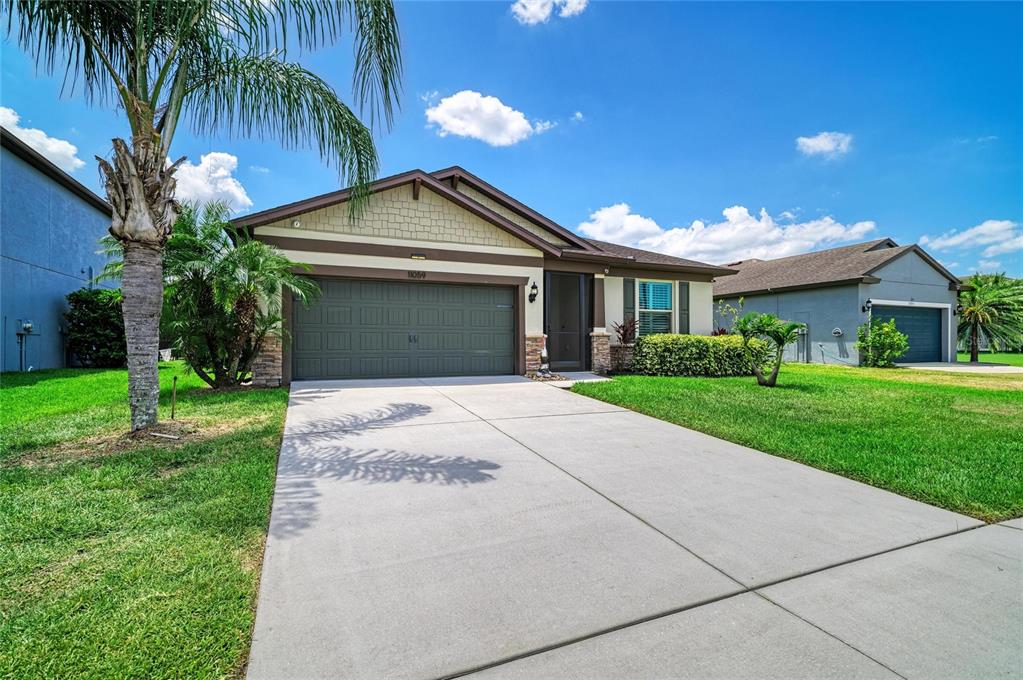 A single-story house with a concrete driveway, a two-car garage, and a palm tree — 11059 58TH STREET CIR E, PARRISH, FL