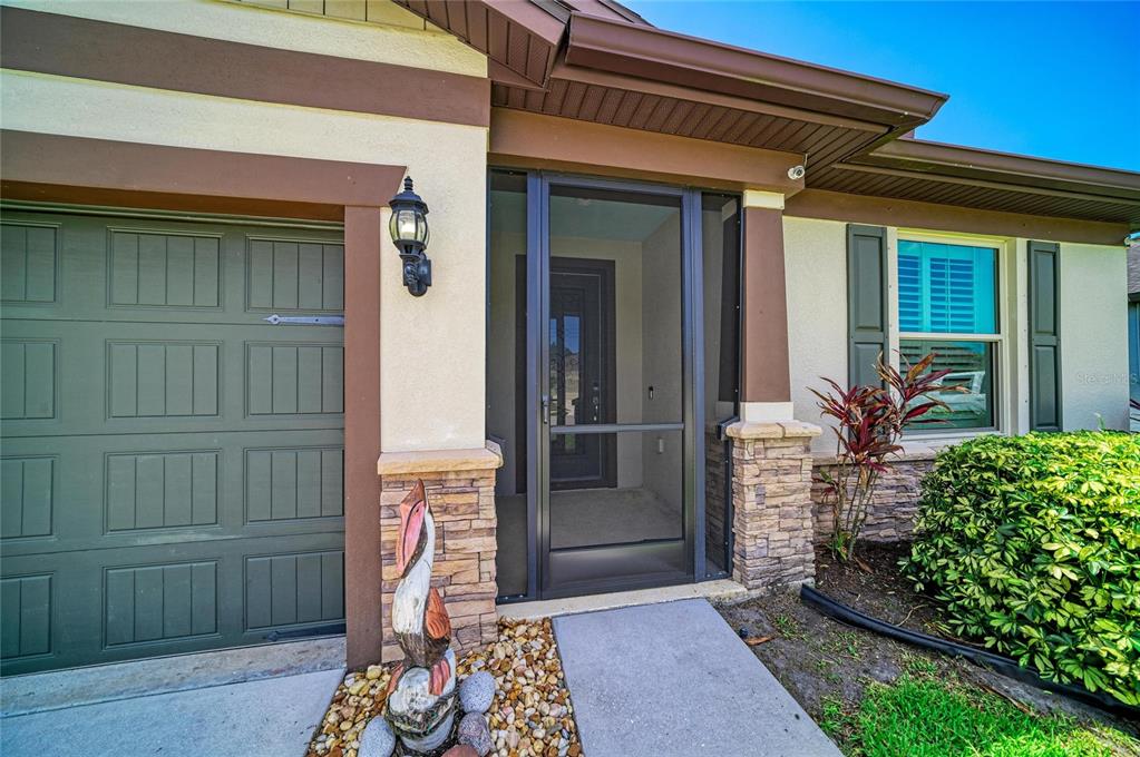 A house exterior features a garage, a screened front entryway, and stone veneer accents — 11059 58TH STREET CIR E, PARRISH, FL