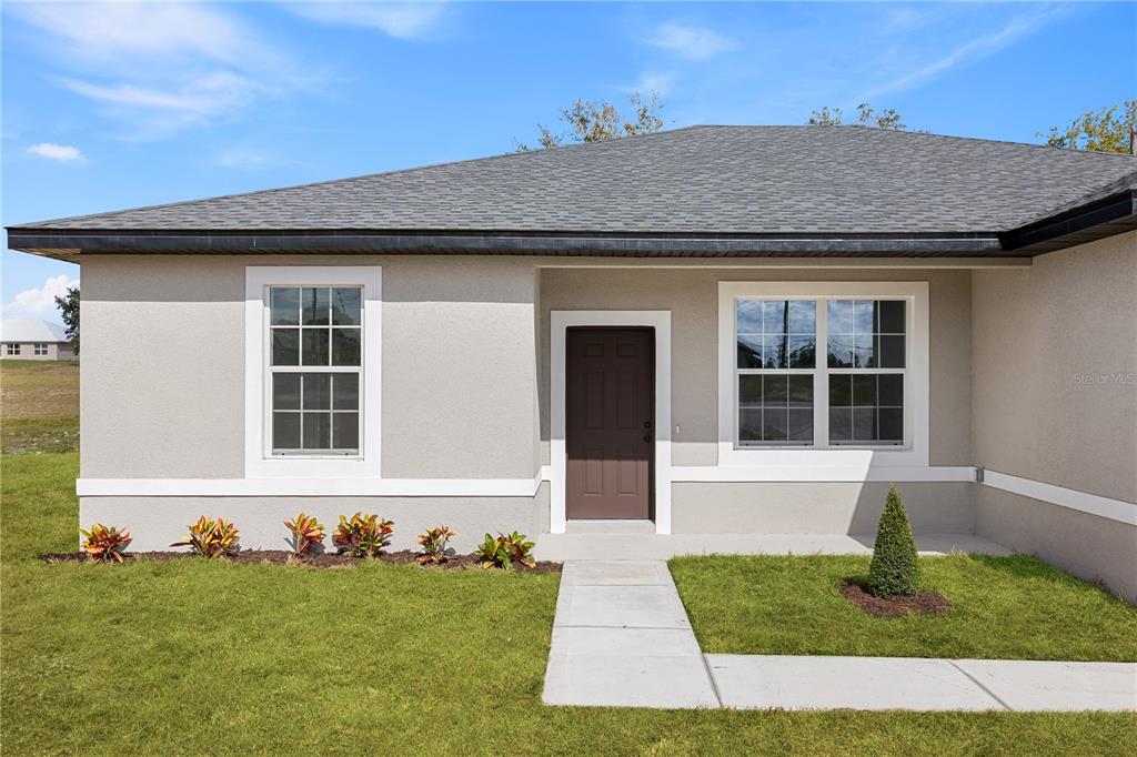 A single-story house with a beige stucco exterior, a dark brown door, and a gray roof — 3261 W GAINESVILLE DRIVE, CITRUS SPRINGS, FL