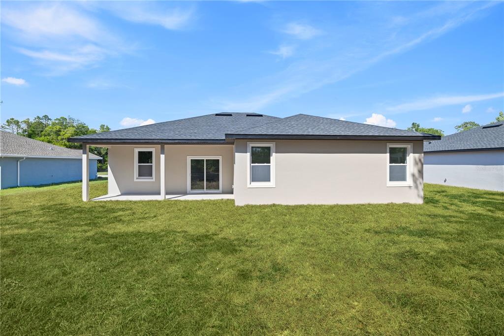 The rear exterior of a single-story house with a covered patio and a grassy yard — 3261 W GAINESVILLE DRIVE, CITRUS SPRINGS, FL