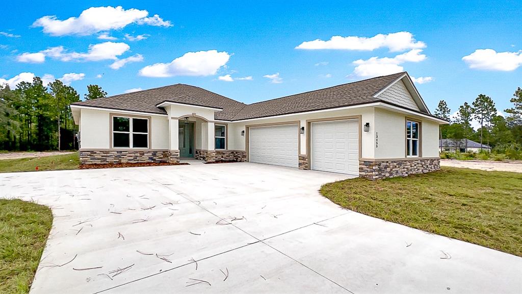A single-story house with a stone-accented facade, two-car garage, and a concrete driveway — TBD SW 98TH STREET, DUNNELLON, FL