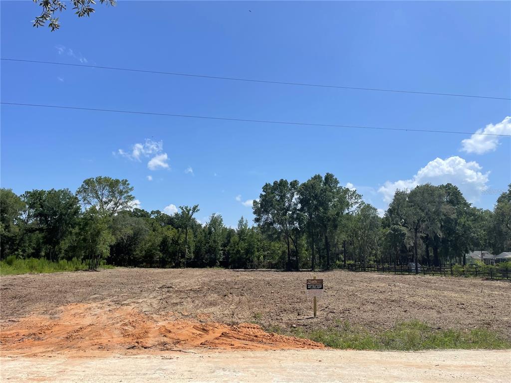 A cleared, vacant lot with a small sign stands before a line of mature trees — TBD SW 98TH STREET, DUNNELLON, FL