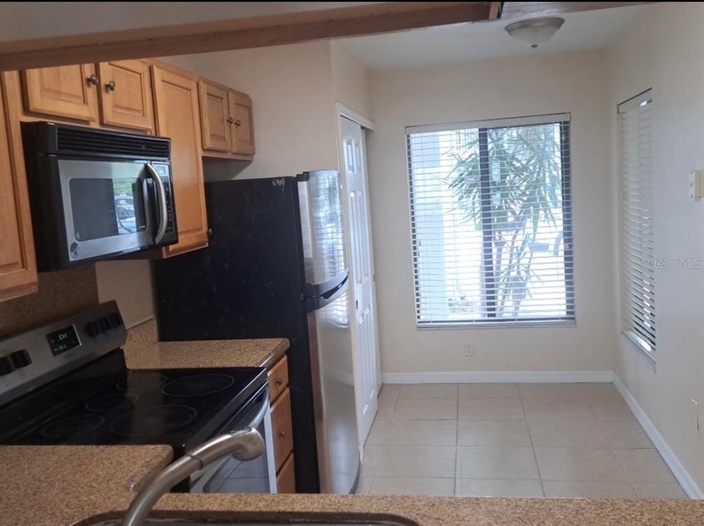 A kitchen with light wood cabinets, black appliances, granite countertops, and a windowed dining area — 2227 STONINGTON AVENUE UNIT 2227, ORLANDO, FL