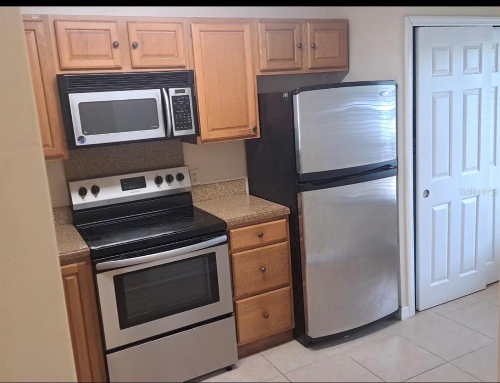 A kitchen features light wood cabinets, stainless steel appliances, and tan speckled laminate countertops — 2227 STONINGTON AVENUE UNIT 2227, ORLANDO, FL