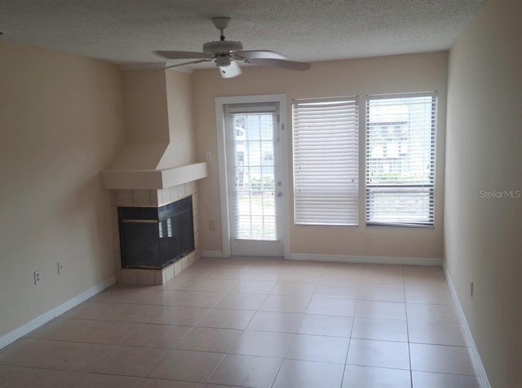 A living room features tile flooring, a corner fireplace, a ceiling fan, and glass doors — 2227 STONINGTON AVENUE UNIT 2227, ORLANDO, FL