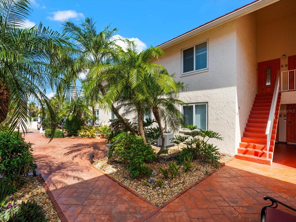 An exterior view of a two-story building with orange stairs and a paved courtyard — 6708 SARASEA CIRCLE UNIT 202, SARASOTA, FL