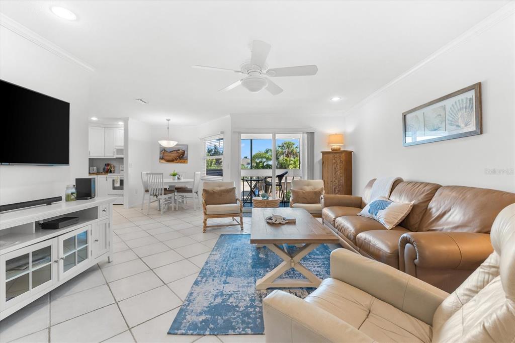 A living room with tile floors, a brown leather sofa, and a blue area rug — 6708 SARASEA CIRCLE UNIT 202, SARASOTA, FL