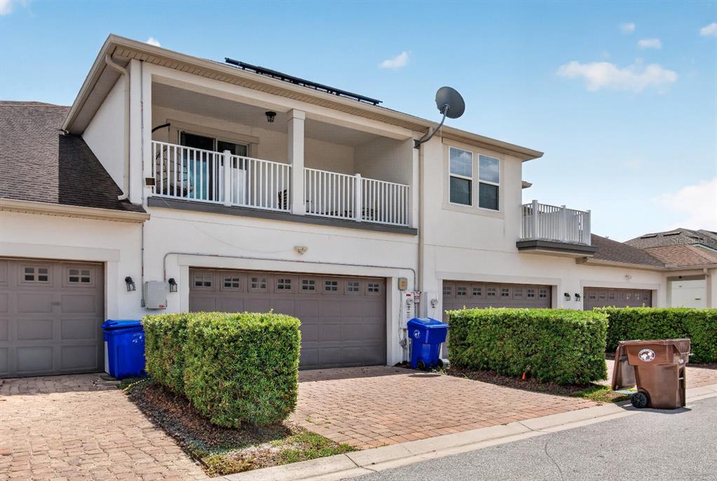 A two-story townhouse exterior features a balcony, a garage, and a paved driveway — 2921 CELLO LANE, KISSIMMEE, FL