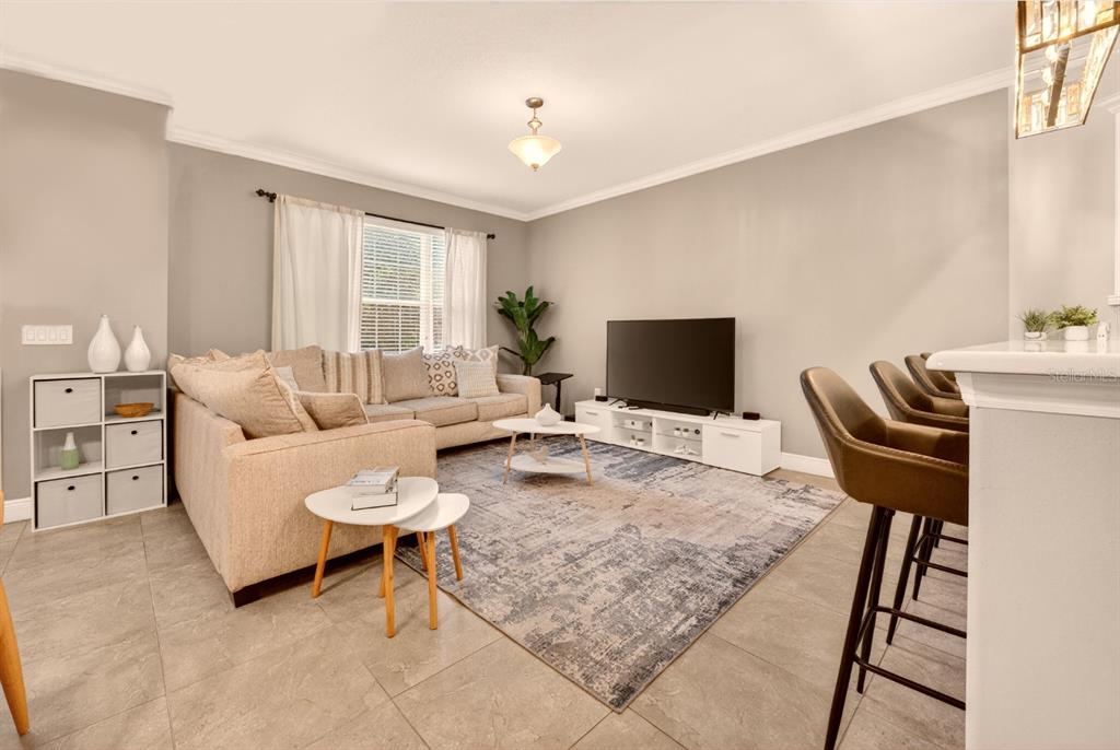 A living room features a beige sectional sofa, a television on a stand, and tile flooring — 2921 CELLO LANE, KISSIMMEE, FL
