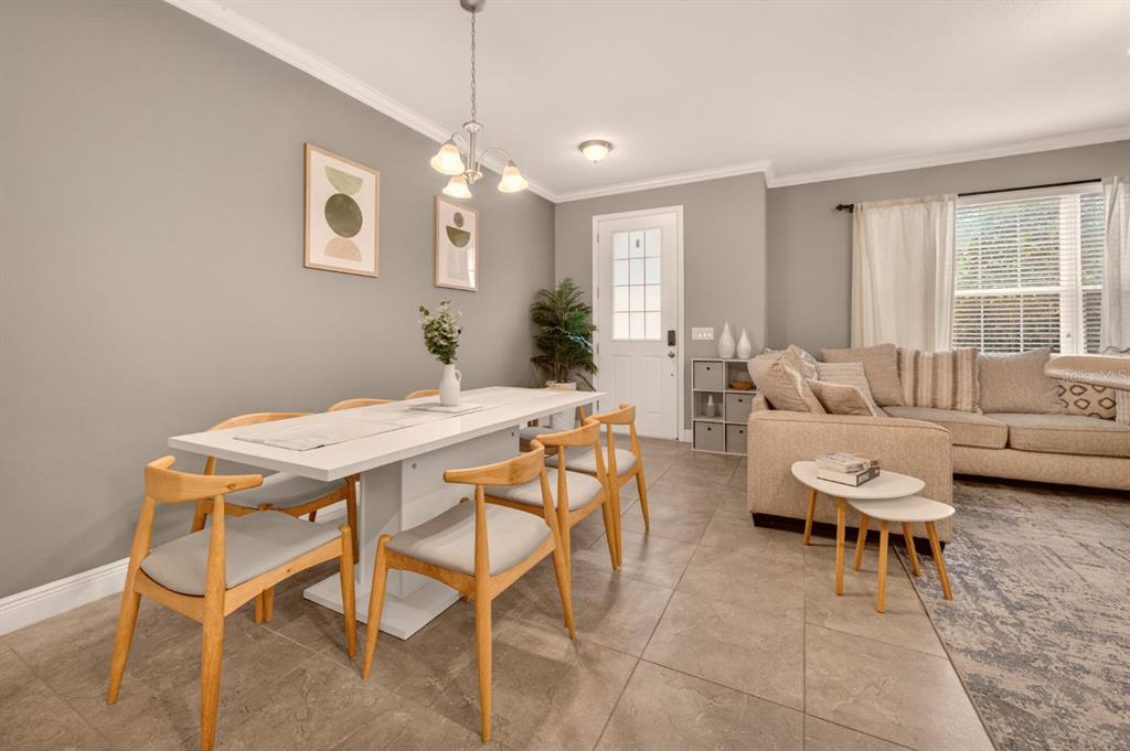 A dining area with a white table and wooden chairs sits beside a living room — 2921 CELLO LANE, KISSIMMEE, FL