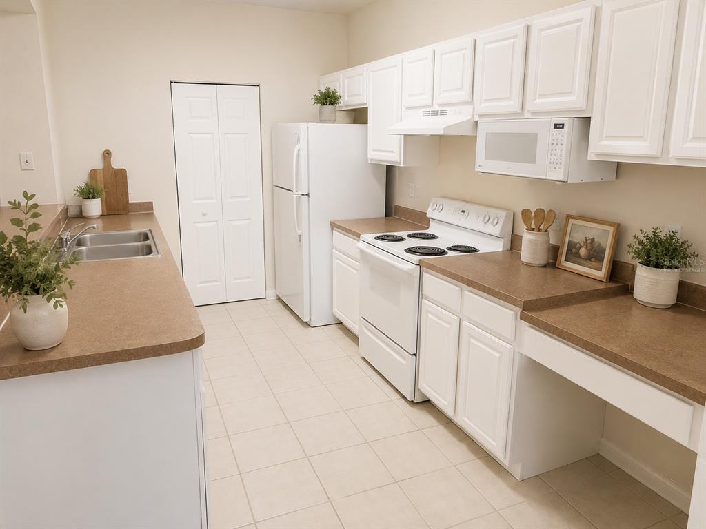 A kitchen features white cabinets, white appliances, and tan countertops with a tiled floor — 5001 SUNRIDGE PALMS DRIVE, TAMPA, FL