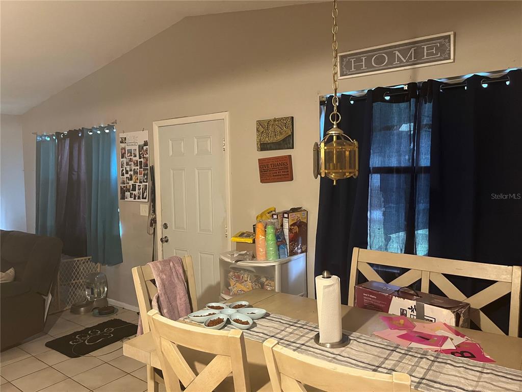 A dining area features a wooden table, chairs, a hanging light fixture, and a white door — 9463 ARBOL COURT, LARGO, FL