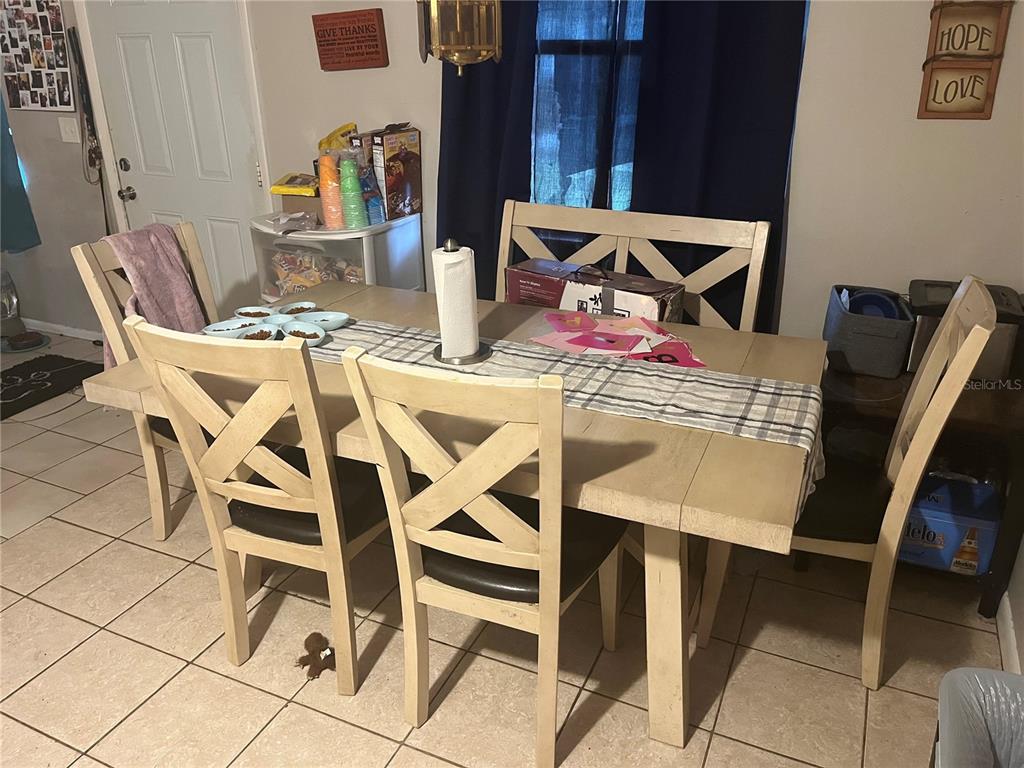 A dining room features a light-colored wooden table with four chairs and a plaid runner — 9463 ARBOL COURT, LARGO, FL