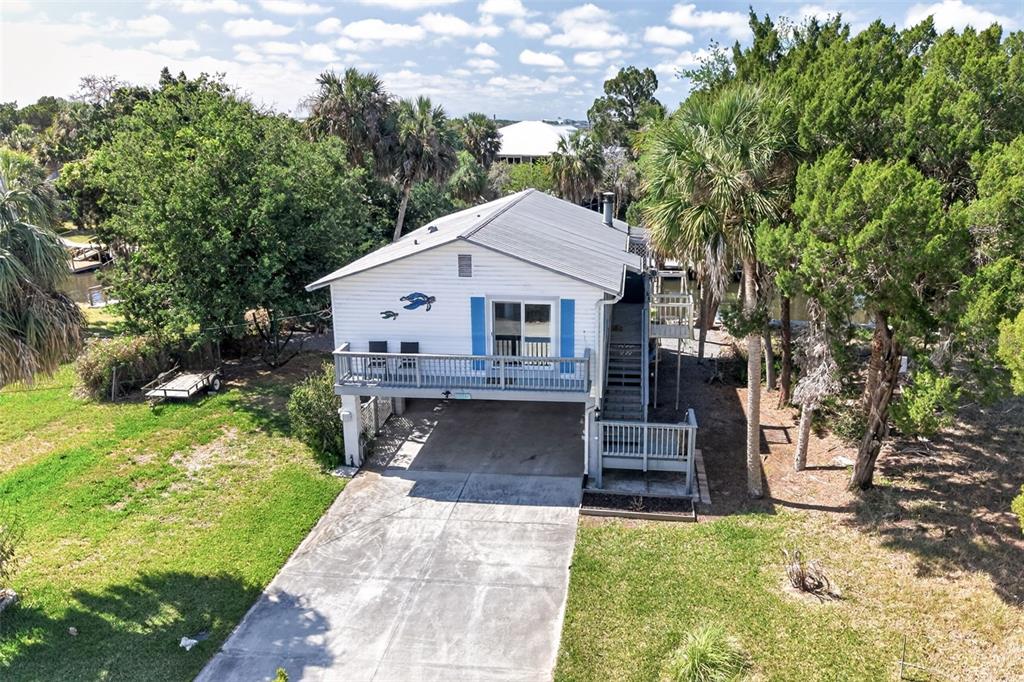 An elevated white house with a metal roof, blue shutters, and a concrete driveway — 12122 W GULF BREEZE COURT, CRYSTAL RIVER, FL