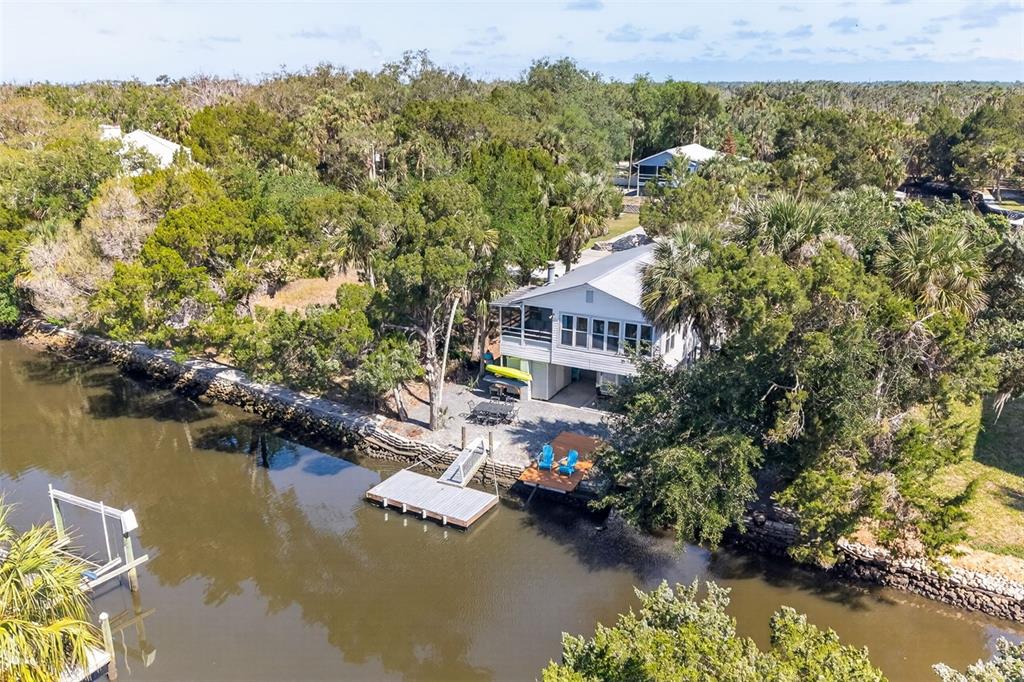 An elevated white house sits along a canal with a private dock and patio area — 12122 W GULF BREEZE COURT, CRYSTAL RIVER, FL