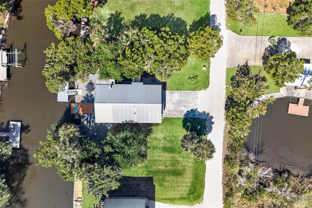 An aerial view shows a house with a metal roof situated between two waterways — 12122 W GULF BREEZE COURT, CRYSTAL RIVER, FL