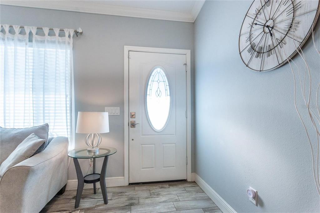 An entryway features a white door with an oval window, tile flooring, and a wall clock — 691 E COUNTRY CLUB DRIVE, WILLISTON, FL