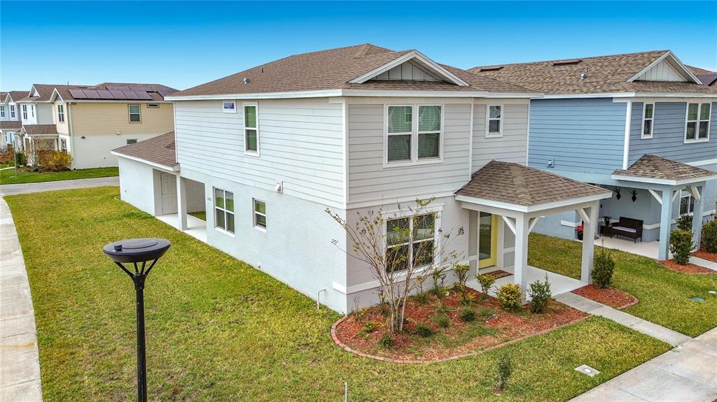 A two-story house with light-colored siding, a covered front porch, and a grassy yard — 1823 SUMMER SERENITY DRIVE, KISSIMMEE, FL