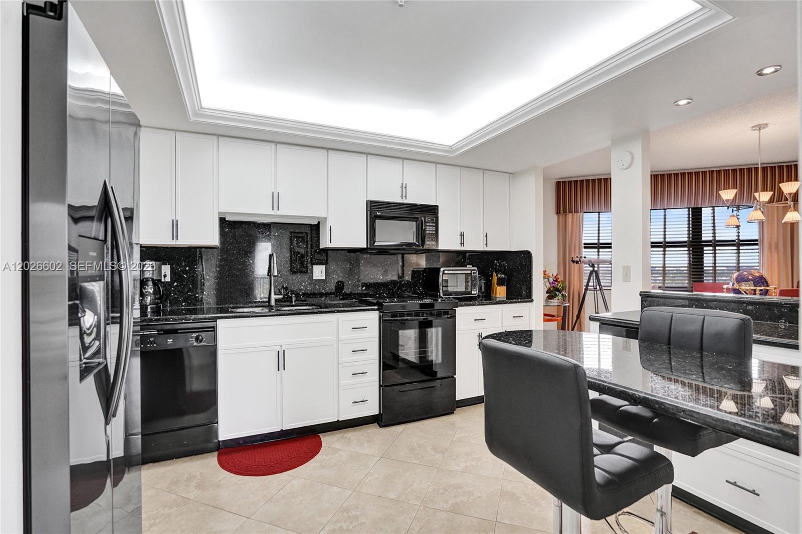 A kitchen features white cabinets, black appliances, and dark granite countertops with a breakfast bar — 501 N Riverside Dr, Pompano Beach FL 33062, POMPANO BEACH, FL