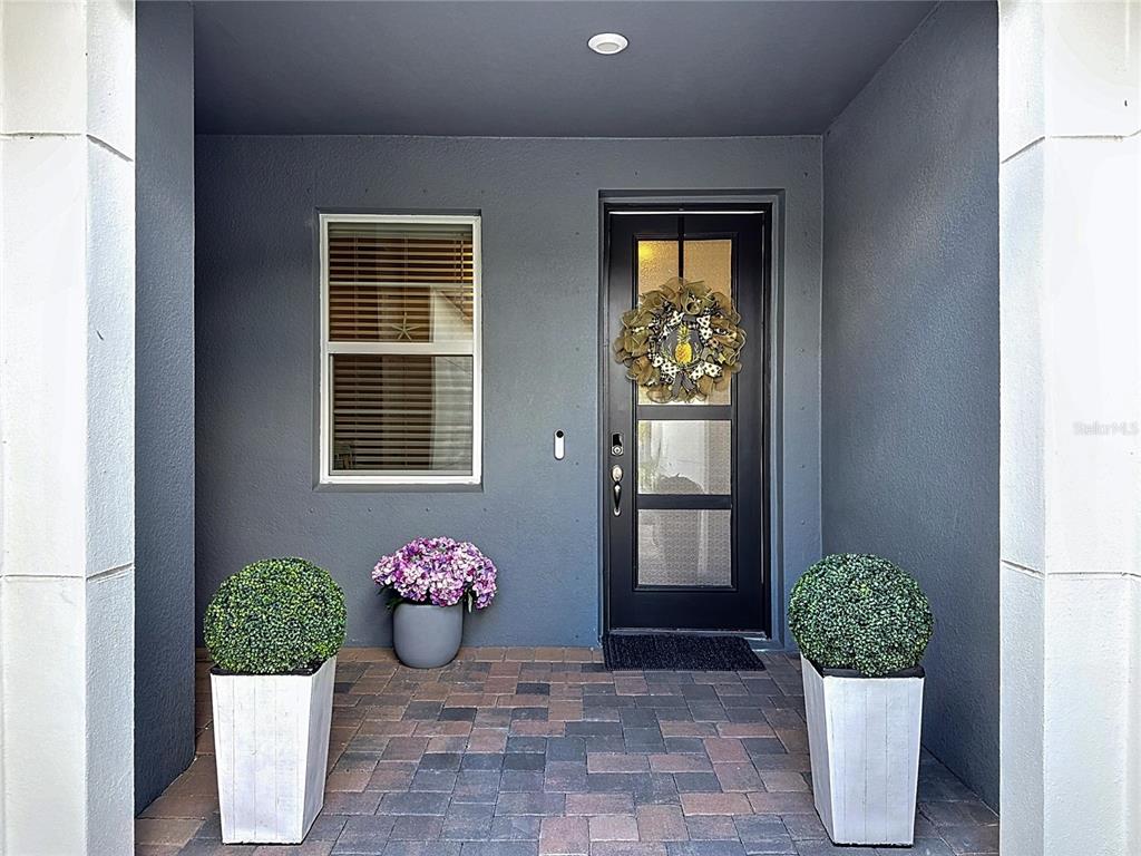 A front porch features a dark gray wall, a glass-paneled door, and two potted topiaries — 3775 MAXWELL PARK DRIVE UNIT 3775, SUN CITY CENTER, FL