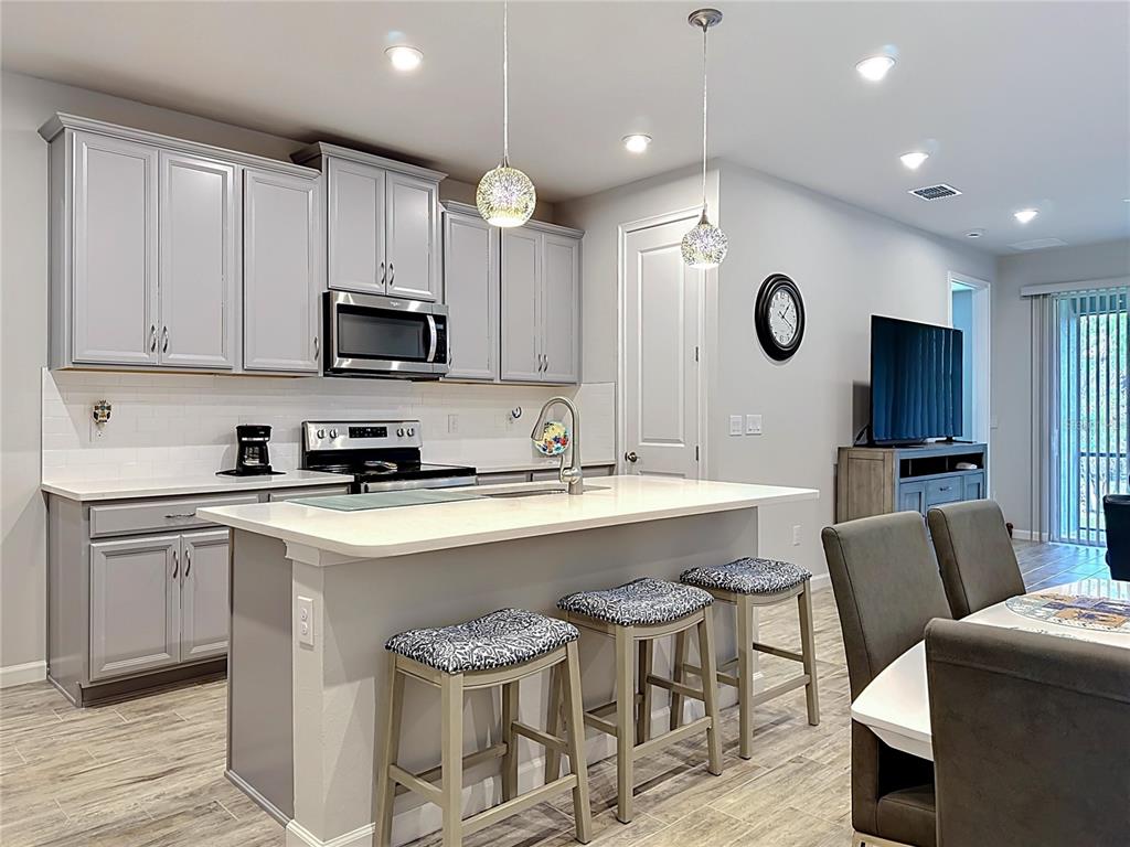 A kitchen with gray cabinets, white countertops, a center island with stools, and tile flooring — 3775 MAXWELL PARK DRIVE UNIT 3775, SUN CITY CENTER, FL