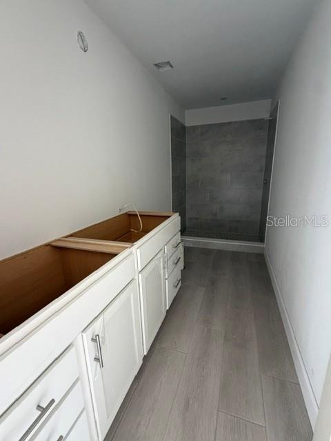An open-concept living area features light wood-look tile flooring and a kitchen with white cabinets — 3036 THORNHILL ROAD, WINTER HAVEN, FL
