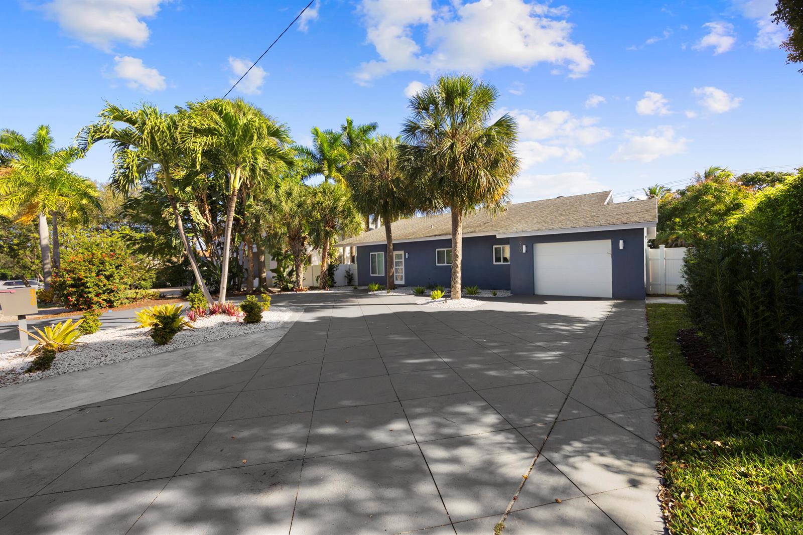 A blue house with a white garage door and palm trees sits behind a paved driveway — 930 NW 4th Court, Boca Raton FL 33432, BOCA RATON, FL