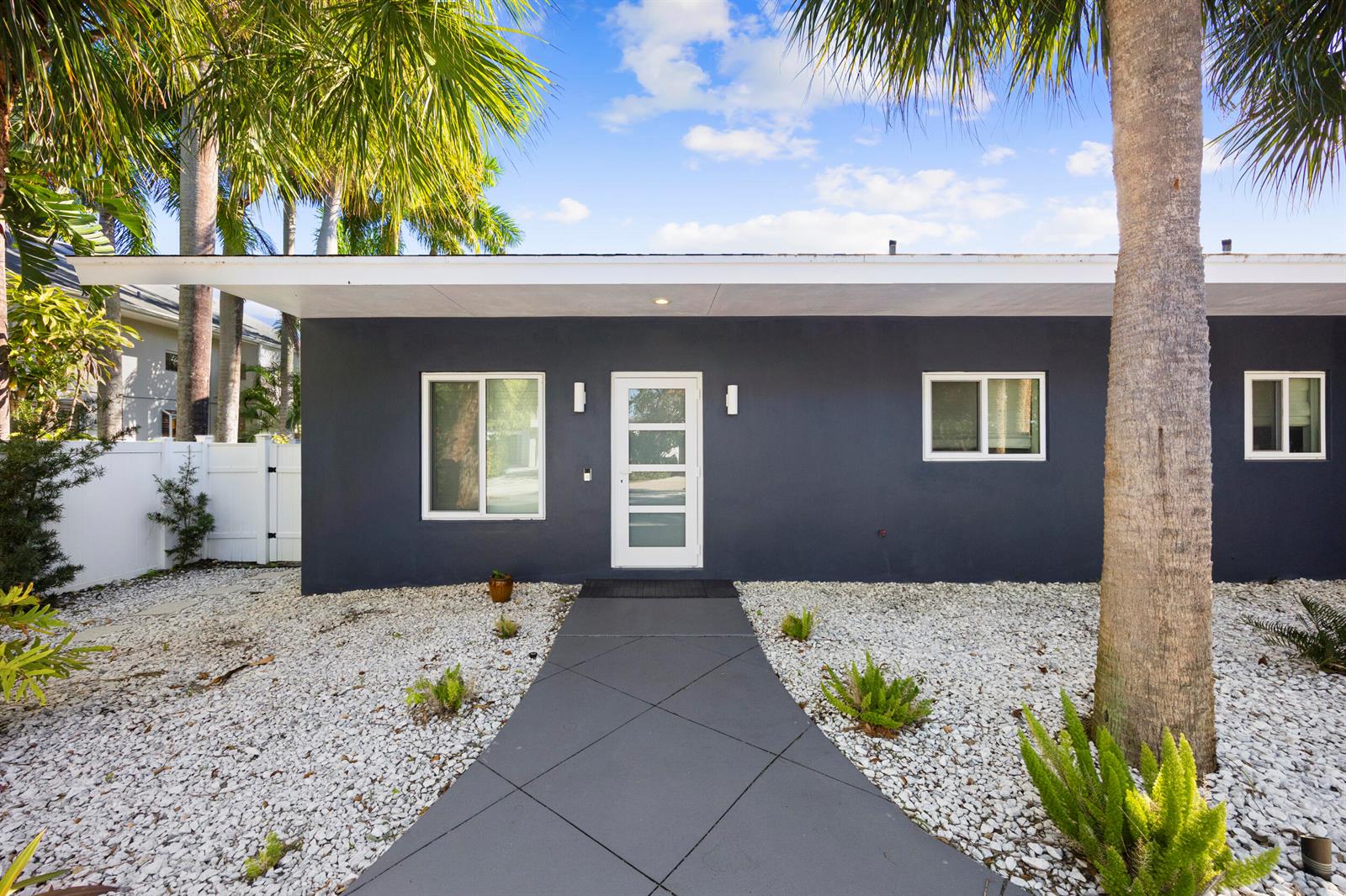 A dark gray house exterior features a white front door, white-framed windows, and gravel landscaping — 930 NW 4th Court, Boca Raton FL 33432, BOCA RATON, FL