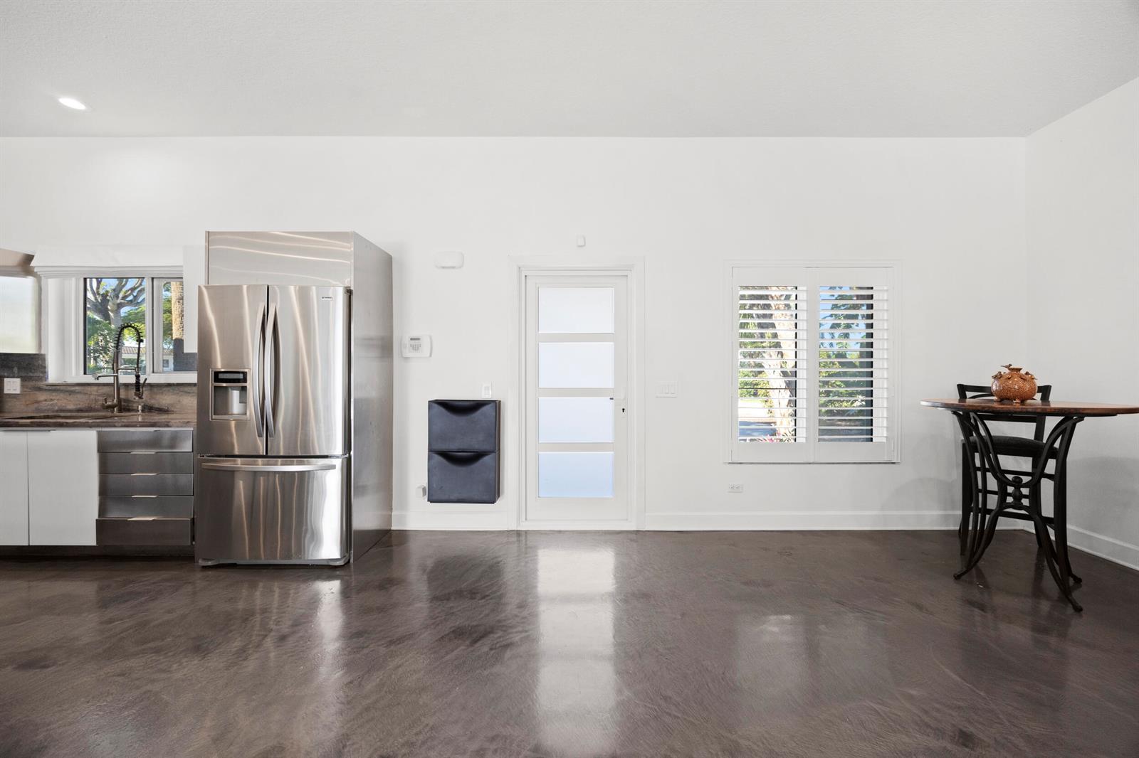 A kitchen and dining area with stainless steel appliances, white walls, and dark polished floors — 930 NW 4th Court, Boca Raton FL 33432, BOCA RATON, FL