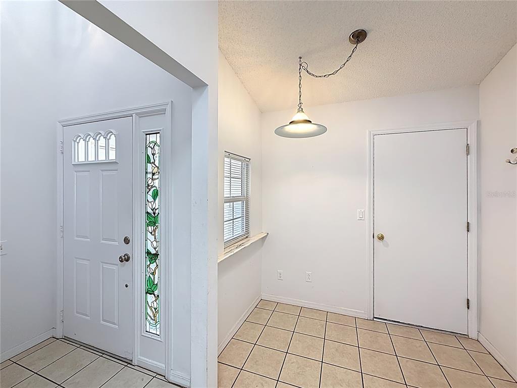 An entryway with tile flooring, a white door with stained glass, and a hanging light — 5932 MCENROE COURT, LEESBURG, FL
