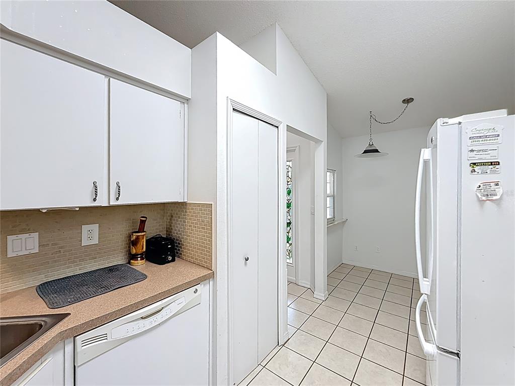 A kitchen features white cabinets, a dishwasher, a tiled backsplash, and an adjacent dining area — 5932 MCENROE COURT, LEESBURG, FL