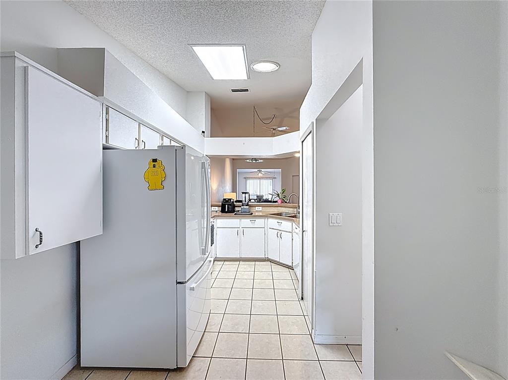 A white kitchen features tile flooring, white cabinetry, and a refrigerator with a yellow magnet — 5932 MCENROE COURT, LEESBURG, FL