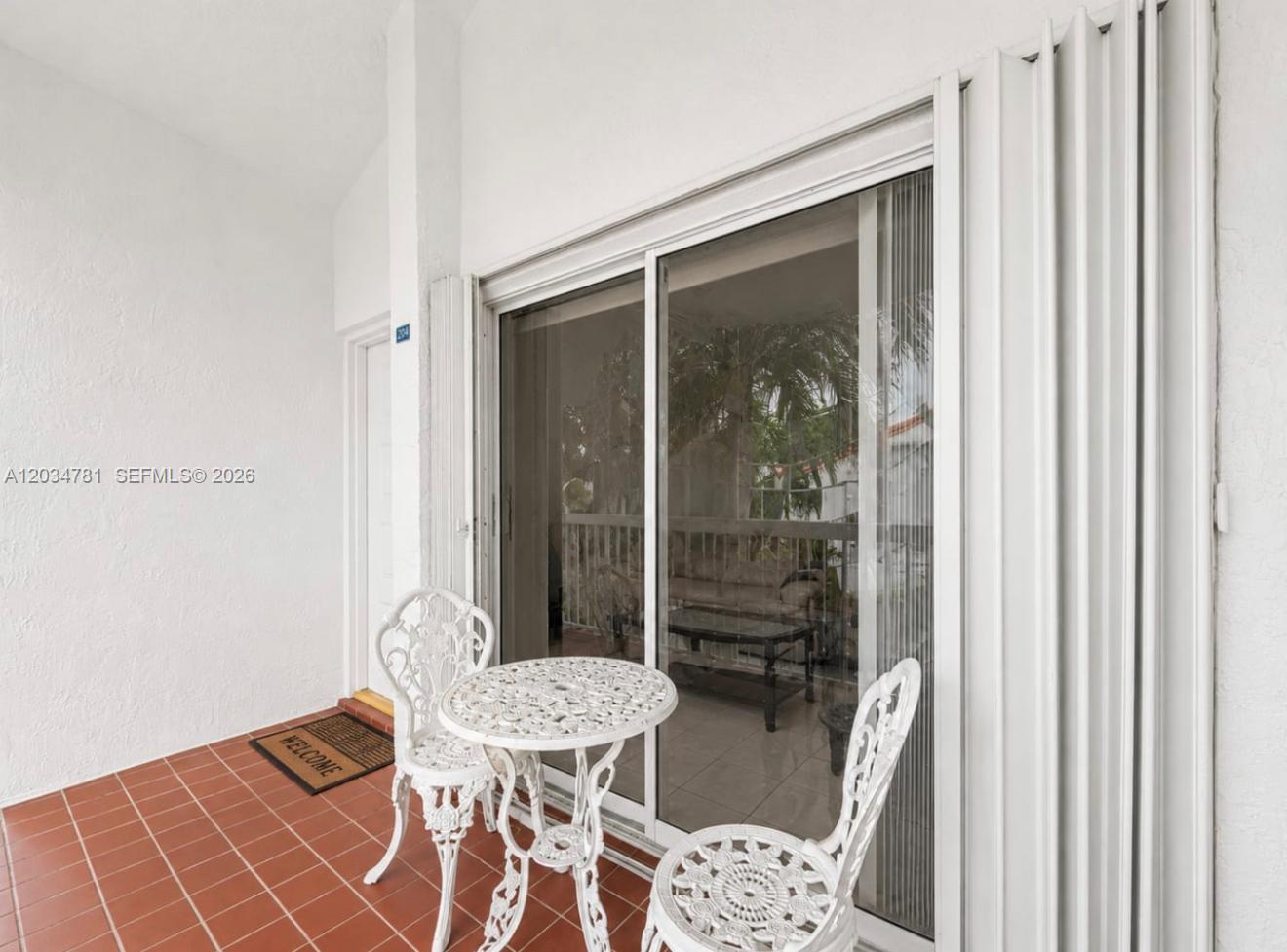 A white patio features a small metal table and two chairs on tiled flooring — 7611 SW 153rd Ct # 204, Miami FL 33193, MIAMI, FL