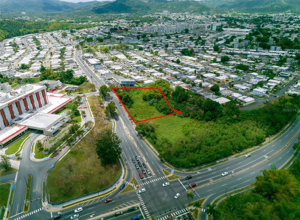 An aerial view shows a vacant, rectangular lot outlined in red next to a hospital — Avenida Luis Muñoz Marin BARRIO TURABO Lote 1, CAGUAS, PR
