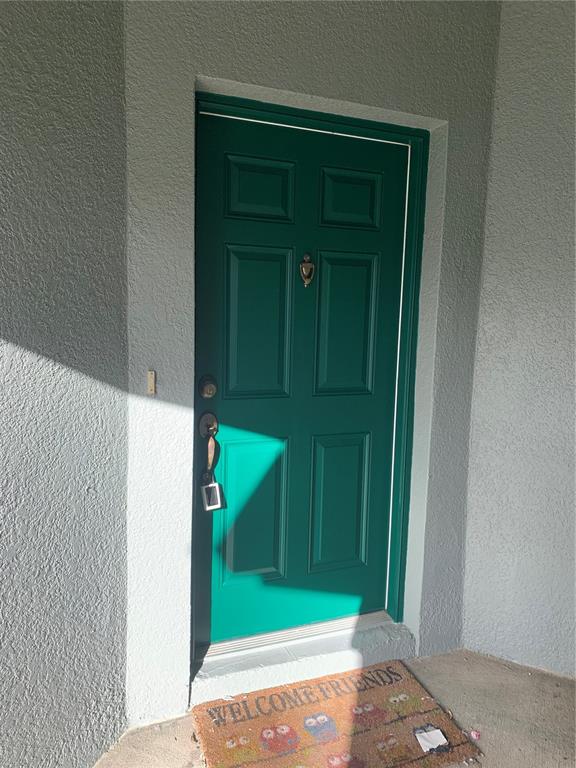 A green six-panel front door with brass hardware sits in a light-colored stucco entryway — 9381 JASMINE FLOWER LANE UNIT 168, ORLANDO, FL