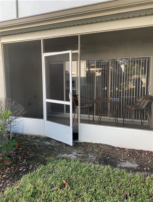 A screened-in patio features a white door, a small table, and two chairs — 9381 JASMINE FLOWER LANE UNIT 168, ORLANDO, FL